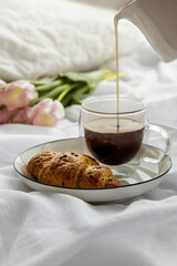 Romantic morning cup of coffee with a croissant in a bedroom.