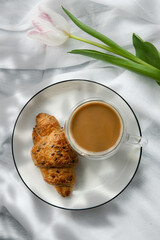 Romantic morning cup of coffee with a croissant on a bed,top view.
