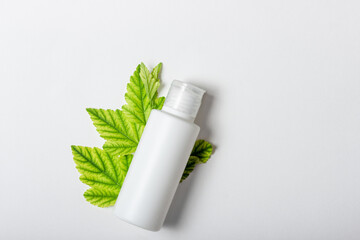 Cosmetic cream for moisturizing and cleansing the face. Cream or face mask in white tubes and leaves of natural plants. White bottle with empty space