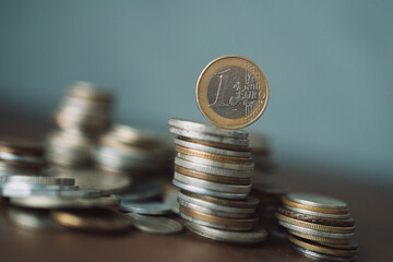 a stack of coins with a euro coin on top against the background of coins of different countries with blur