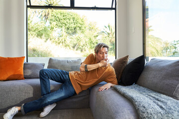 Fototapeta premium Man with hands touching face on sofa by window