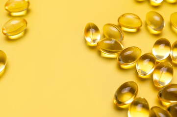 Fototapeta na wymiar Capsules pill with vitamin D on yellow background close-up. Fish oil, Omega, Omega-3, dietary supplement, sunshine vitamin. Healthy lifestyle, medicine, cosmetology, diet. Pharmaceutical concept