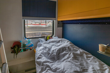 Blue and yellow interior of sleeping coach with sleeping man