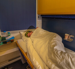 Blue and yellow interior of sleeping coach with sleeping man