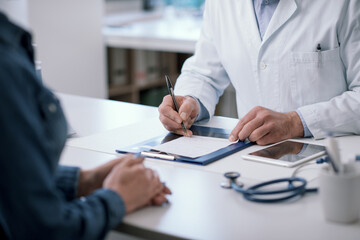 Doctor writing a medical prescription for his patient - obrazy, fototapety, plakaty