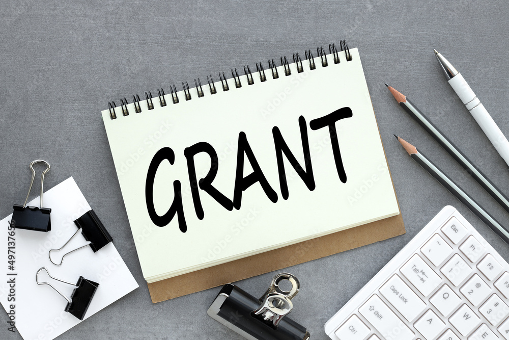 Poster grants. text on open notebook near white keyboard and pencils