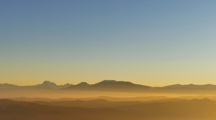 Un mare di luce dorata al tramonto colora le montagne e le colline e riempie le valli 