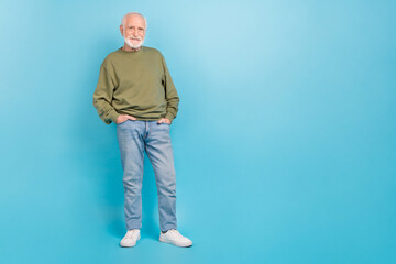 Full length body size view of attractive cheerful grey-haired man holding hands in pockets isolated over vivid blue color background