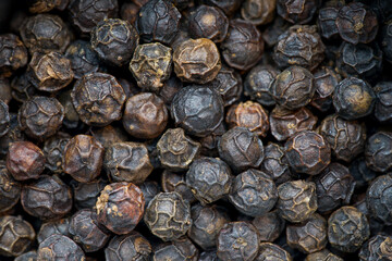 Whole black pepper. Detail on the grains, no background. Macro shot.