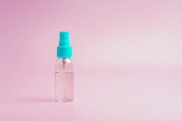 Transparent spray bottle filled with clear liquid on a pink background