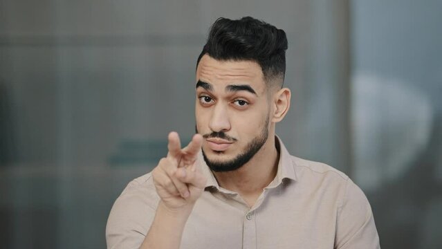 Serious man arabian worker entrepreneur upset nodds head pointing fingers on both eyes showing watching you gesture follow sign at camera hispanic businessman warning colleague demonstrate distrust