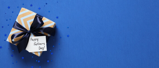 Happy Fathers Day wide banner design. Father's Day sale, discount concept. Vintage gift box with blue ribbon bow and label Happy Fathers Day.