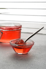 red fruity jelly in glass jar and spoon