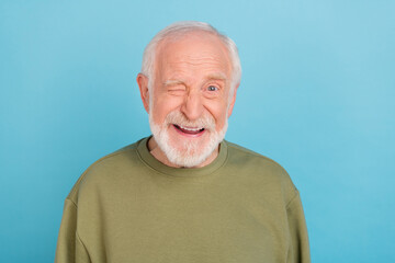 Portrait of attractive cheerful coquettish grey-haired man winking isolated over vivid blue color...
