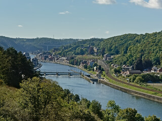 River Meuse with sluice, surrounded by hills with forests and houses on the embankments near the city of Dinant, Wallonia, Belgium 