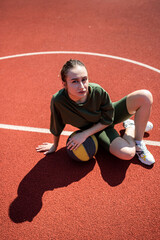 charming young woman wear sport cloth with a basketball is resting after a workout.