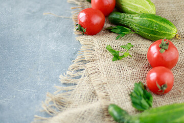 Fototapeta na wymiar Culinary background, home cooking concept. Ripe tomatoes, cucumbers, on burlap, herbs and spices on a wooden background, top view, copy space