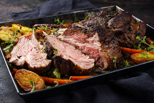 Traditional barbecue rack of lamb with carrot and potatoes served as close-up on a rustic metal tray