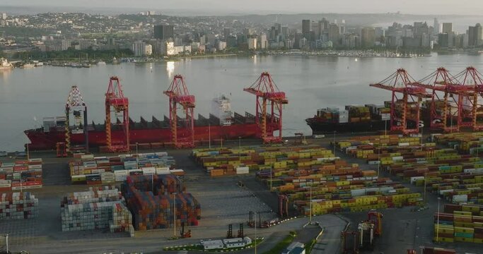 Aerial close-up fly over view of container ships and containers on the docks at Durban harbour, Durban skyline in the background,South Africa