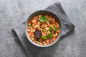 Popular spanish fabada stew with haricot, chorizo, morcillas or blood sausage on gray stone...