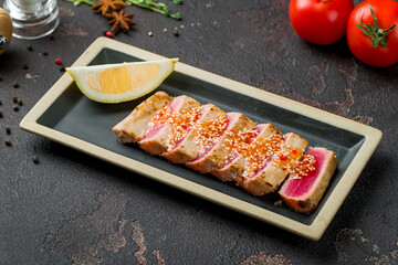 grilled tuna fillet on plate on dark concrete table