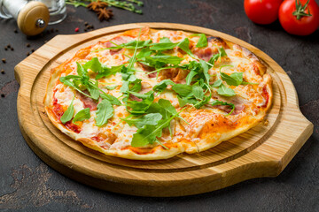 pizza with bacon and aragula on dark concrete table