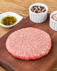 Raw meat hamburger over wooden board with seasonings