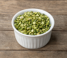 Raw dried green peas in a bowl over wooden table