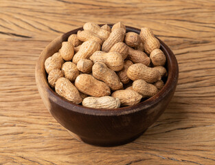 Shelled peanuts on a bowl over wooden table
