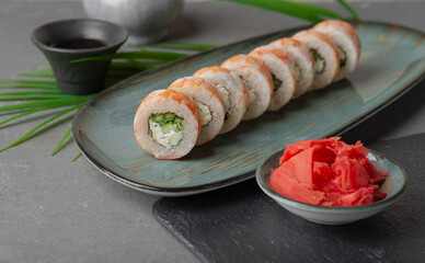 Uramaki sushi rolls on gray plate and gray background with garnish