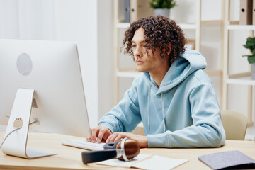 Fototapeta premium guy with curly hair sitting in front of the computer internet online technologies