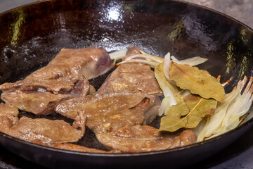 Cook roasts calf liver with onion and bay leaf