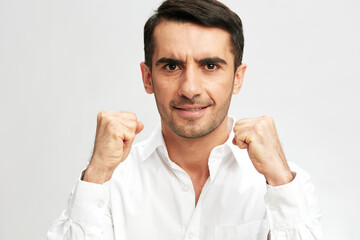 Fototapeta premium handsome businessman white shirt posing holding fists in front of him emotions light background