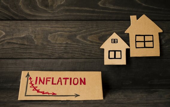 On a wooden background, the inscription on the cardboard inflation and models of houses.  The concept of inflation in the change in housing prices, increasing the interest rate on mortgages.