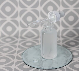 Cosmetic glass bottle with pipette on tile background