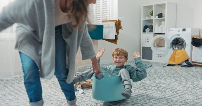 Mom is playing with son who is sitting in laundry bowl little boy wants to spend time with woman and help with household chores mother drags man around laundry room for fun in bowl