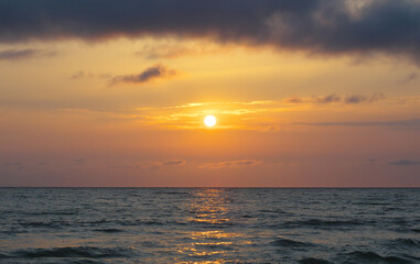  Bright beautiful sunset at the calm sea. Solar disk over water.