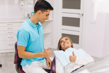 Dentist and woman show each other thumb and smile