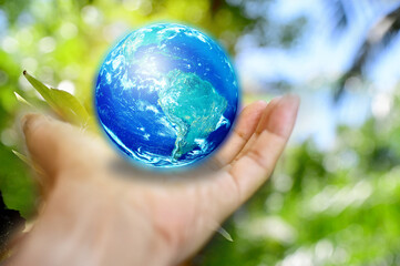Human Hand holding Earth ball on green bokeh background. Concept of World Environment Day, Save the Earth, Preserve Nature, energy in nature. Elements of this image furnished by NASA.