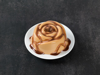 Coffee Panna Cotta with chocolate sauce, in the shape of a rose, on a plate. Dark gray background