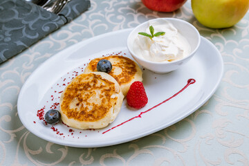 cheesecakes from cottage cheese with sour cream and berries on white plate