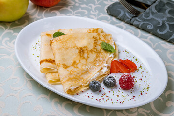 Pancake with cottage cheese and berries on a white plate