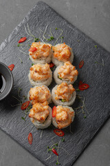 Uramaki rolls with red fish and garnish on a gray background