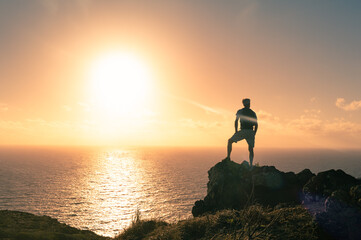 Fototapeta premium Silhouette of a person on the top of the mountain looking out to the sunrise. 