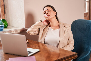 Psychologist closed her eyes and rubbing her neck after hard work day