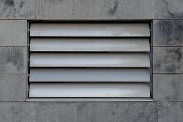 Steel ventilation shutters on a concrete tile facade, metal louvers