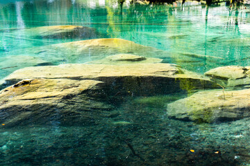 rocks in a green water Lake with saiblings