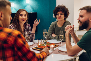 Group of friends enjoying dinner while sitting at the kitchen table together