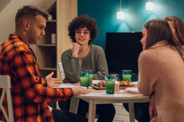 Group of friends enjoying dinner while sitting at the kitchen table together