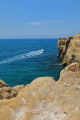 Fototapeta na wymiar Motorboat passing next to the shore-rugged rocky cliff-Algar Seco. Carvoeiro-Portugal-183